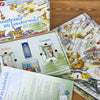 „Abenteuer im Liederwald“ Edition Kinderlieder von Brettschneider Verpackungen GmbH ist ein fesselndes Brettspiel mit illustriertem Waldthema, bestehend aus Spielbrett, „Aktion“- und „Ereignis“-Karten, Anleitung, Würfeln und Spielsteinen – alles elegant arrangiert auf einer Holzoberfläche – ein Abenteuer, das darauf wartet, sich zu entfalten.