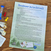 Die deutsche Spielanleitung für das Brettspiel „Abenteuer im Liederwald“ von Brettschneider Verpackungen GmbH befindet sich auf einem Holztisch mit einer Sanduhr, blauen und roten Spielbrettsteinen und einem gelben Würfel. Regeln und Ziele sind beschrieben, und auf der Seite sind teilweise Spielkarten sichtbar.