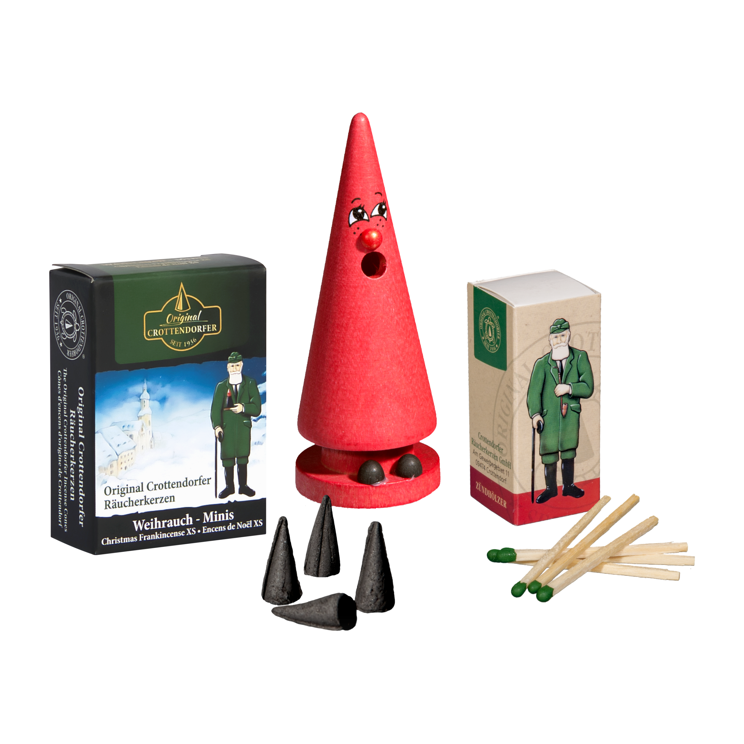 Eine rote kegelförmige Holzfigur mit Gesicht steht neben einem Mini-Räucherset „Romy Rose“ und einer Original Crottendorfer-Dose mit einem Mann in Grün. Im Vordergrund liegen verstreut drei Mini-Räucherkerzen und mehrere Streichhölzer.