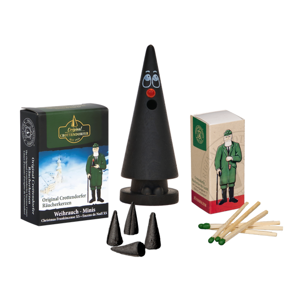 Das Mini-Räucherset „Der kleine Willy“ von Original Crottendorfer Räucherkerzen enthält eine bezaubernde Zwergen- oder Weihnachtswichtelfigur, kegelförmige Räucherkegel und zwei Streichholzschachteln mit der Aufschrift „Crottendorfer Streichhölzer“ und abgebildeten Figuren, von denen eine einem Soldaten ähnelt. Der Verpackungstext ist in deutscher Sprache.