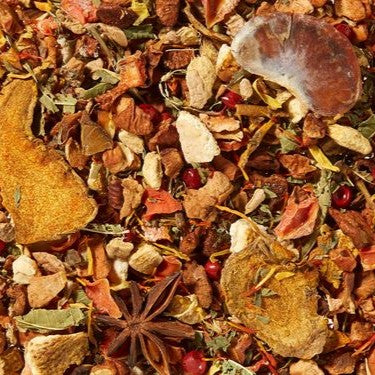 Eine Nahaufnahme von Original Crottendorfer's Gewürzteemischung "Heidis Gewürztee" zeigt eine lebendige Mischung mit getrockneten Fruchtscheiben, Sternanis, ganzen Gewürzen, Kurkuma Ingwer Zimt, sowie bunten Kräutern und Blüten.