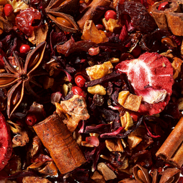 Eine Nahaufnahme der Original Crottendorfer Früchteteemischung "Winterbeerchen", eine lebendige Mischung mit Trockenfrüchten, Sternanis, Zimtstangen, rosa Pfefferkörnern und Hibiskus - ideal für festliche Früchtetee-Weihnachtsmomente.
