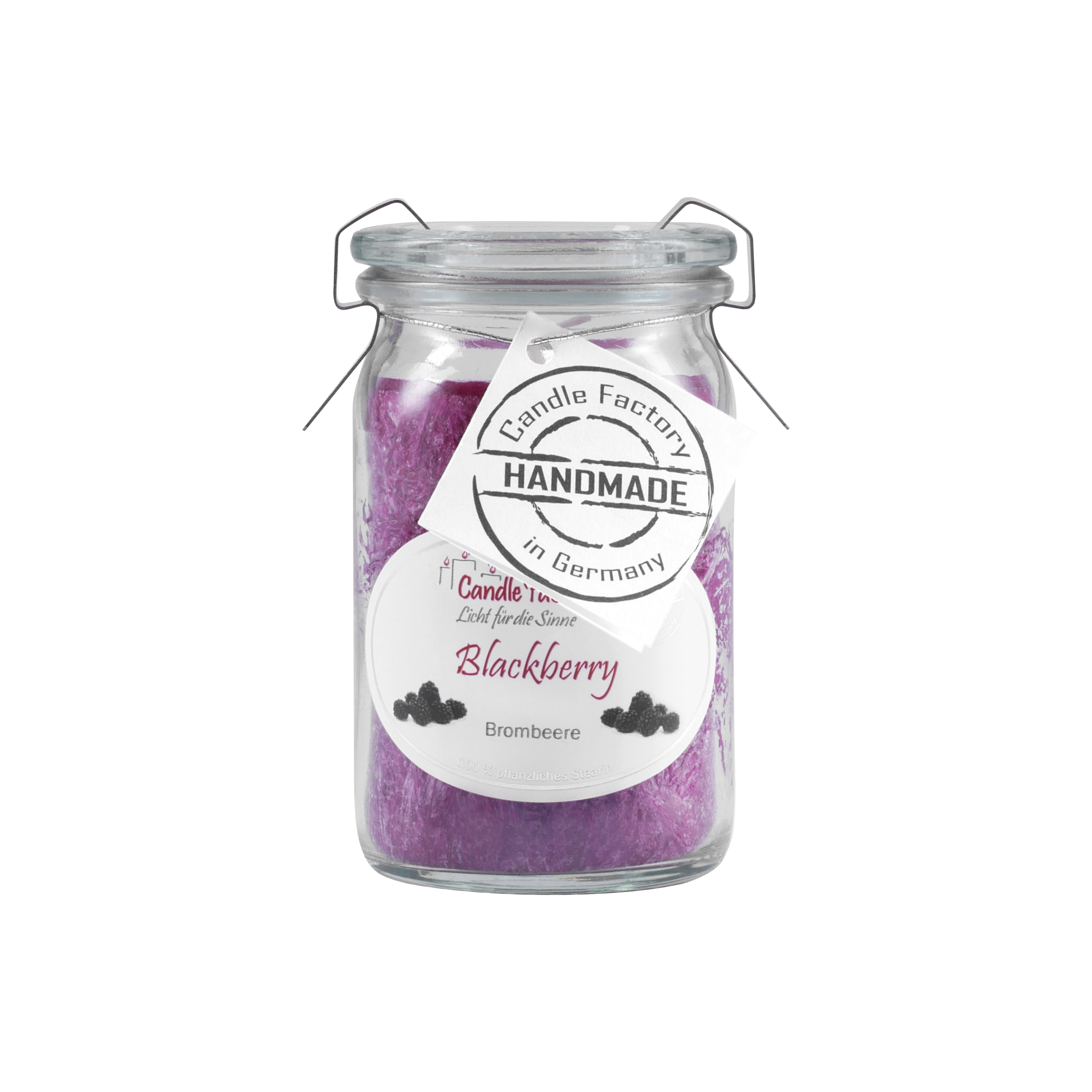 Eine Candle Factory „Blackberry“ Duftkerze/Windlicht im Glasgefäß, mit sattem violettem pflanzlichem Stearinwachs mit Brombeer-Note, inklusive kleinem Etikett um den Hals und „Handmade in Germany“.