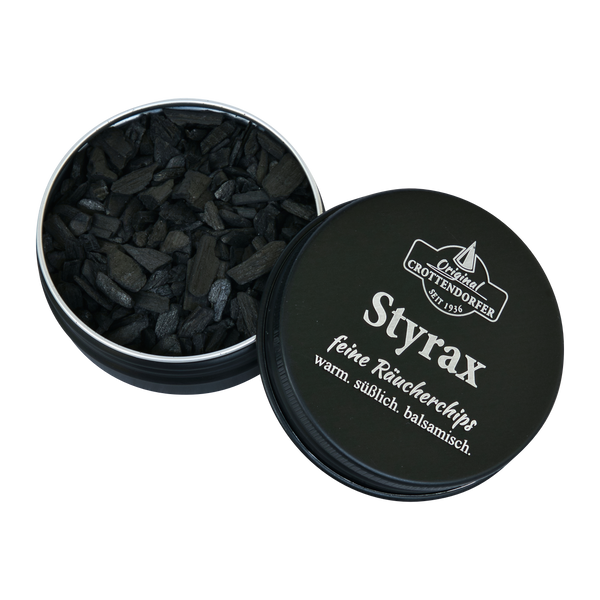 Eine schwarze Schraubdeckeldose mit der Aufschrift "Räucherchips Styrax 10 g in der Schraubdeckeldose" von Original Crottendorfer Räucherkerzen enthält kleine, dunkle Räucherchips, die im Deutschen als warm, süß und balsamisch beschrieben werden.