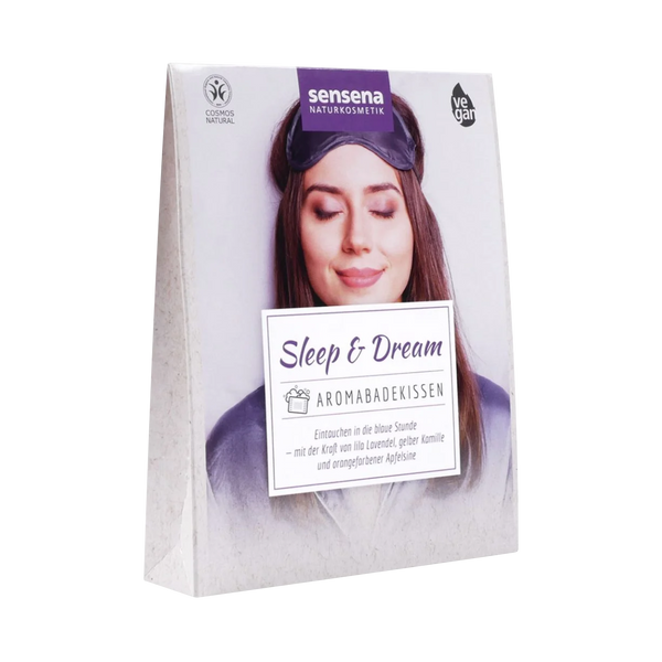 Das Aromabadekissen "Sleep & Dream" von Original Crottendorfer besticht durch beruhigende Düfte und natürliche, vegane Inhaltsstoffe auf seiner Verpackung, die eine entspannte Frau in einer Schlafmaske zeigt, um das wohltuende Badeerlebnis zu unterstreichen.