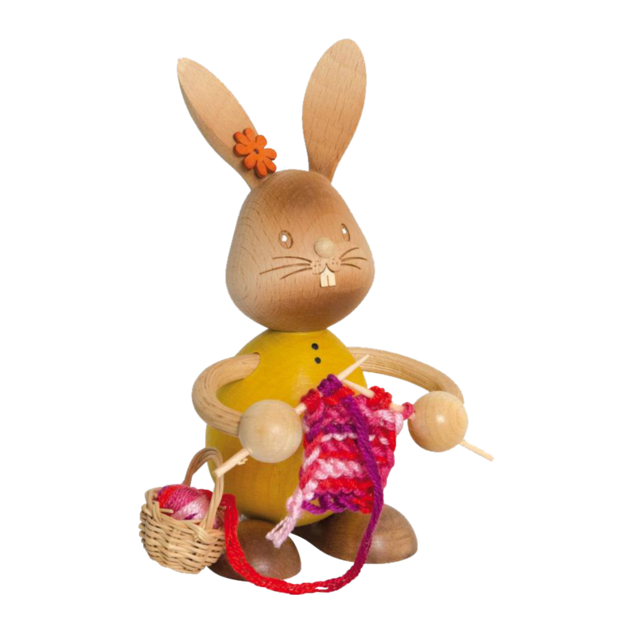 Der Stupsi Hase mit Strickzeug von Drechslerei Kuhnert ist eine handgefertigte Hasenfigur aus Holz, die mit rotem und rosa Garn strickt. Er trägt ein gelbes Hemd, eine orangefarbene Blume am Ohr und hält Stricknadeln, während daneben ein kleiner Korb mit Garnknäueln steht.