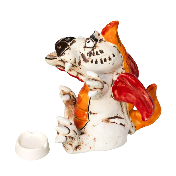 Der „KU Drache BOOH!“ von Kurilin DECO ist ein Keramikdrache mit orangen und roten Flügeln, der verspielt mit offenem Maul sitzt. Sein weißer Körper weist schwarze Sprenkel und Umrisse auf, dazu gibt es eine kleine weiße Schale für Räucherwerk.