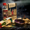Ein Set im Vintage-Stil umfasst eine Flasche Kräuterbitter, eine Schachtel Räucherkegel und Streichhölzer mit grüner Spitze. Eine kleine braune Keramikschale enthält rauchende Räucherkerzen – alles schön arrangiert auf einer rustikalen Oberfläche – und erinnert an den Charme des Original Crottendorfer Geschenksets Grubenfeuer.
