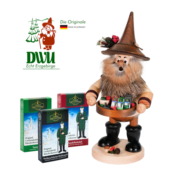 Der Original Crottendorfer Räucherkerzenverkäufer, eine bärtige Holzfigur mit braunem Hut und Pfeifen, verkörpert die Handwerkskunst der DWU Drechselwerkstatt Uhlig. Begleitet von drei bunten Räucherkerzen-Boxen mit deutschem Text und einem Logo oben links mit einem grünen Baum und der deutschen Flagge.