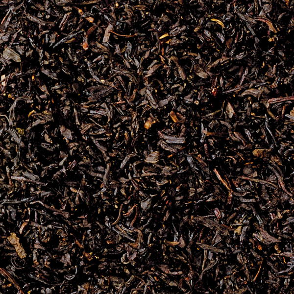 Eine Nahaufnahme des Schwarztees „Raacherkerzl-Tee“ von Original Crottendorfer zeigt lose schwarze Teeblätter mit einer satten, dunklen Farbe und einer gekräuselten, getrockneten Textur, die mit ihrem Hauch von Bergamotte-Essenz ein dichtes Aussehen ähnlich dem klassischen Earl Grey erzeugt.