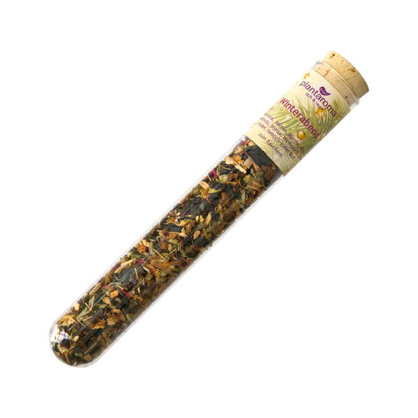 Ein transparentes Reagenzglas mit Korkverschluss enthält eine bunte Mischung aus getrockneten Kräutern und Blütenblättern. Auf dem Etikett steht „Plantaroma Kräutertee“ und der Inhalt wird als „Räuchermittel ‚Winterabend‘“ beschrieben. Es verspricht ein stimmungsvolles Erlebnis, ähnlich wie die Räucherkomposition.
