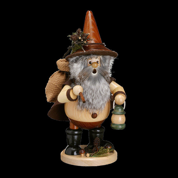 Der Waldwichtel Wanderer natur von DWU Drechselwerkstatt Uhlig ist eine hölzerne Räuchermann-Figur aus dem Erzgebirge, die einen bärtigen Mann mit konischem Hut, Laterne, Pfeife, Mantel und Sack auf dem Rücken darstellt. Er steht anmutig auf einem runden Sockel, der mit Tannenzapfen verziert ist.
