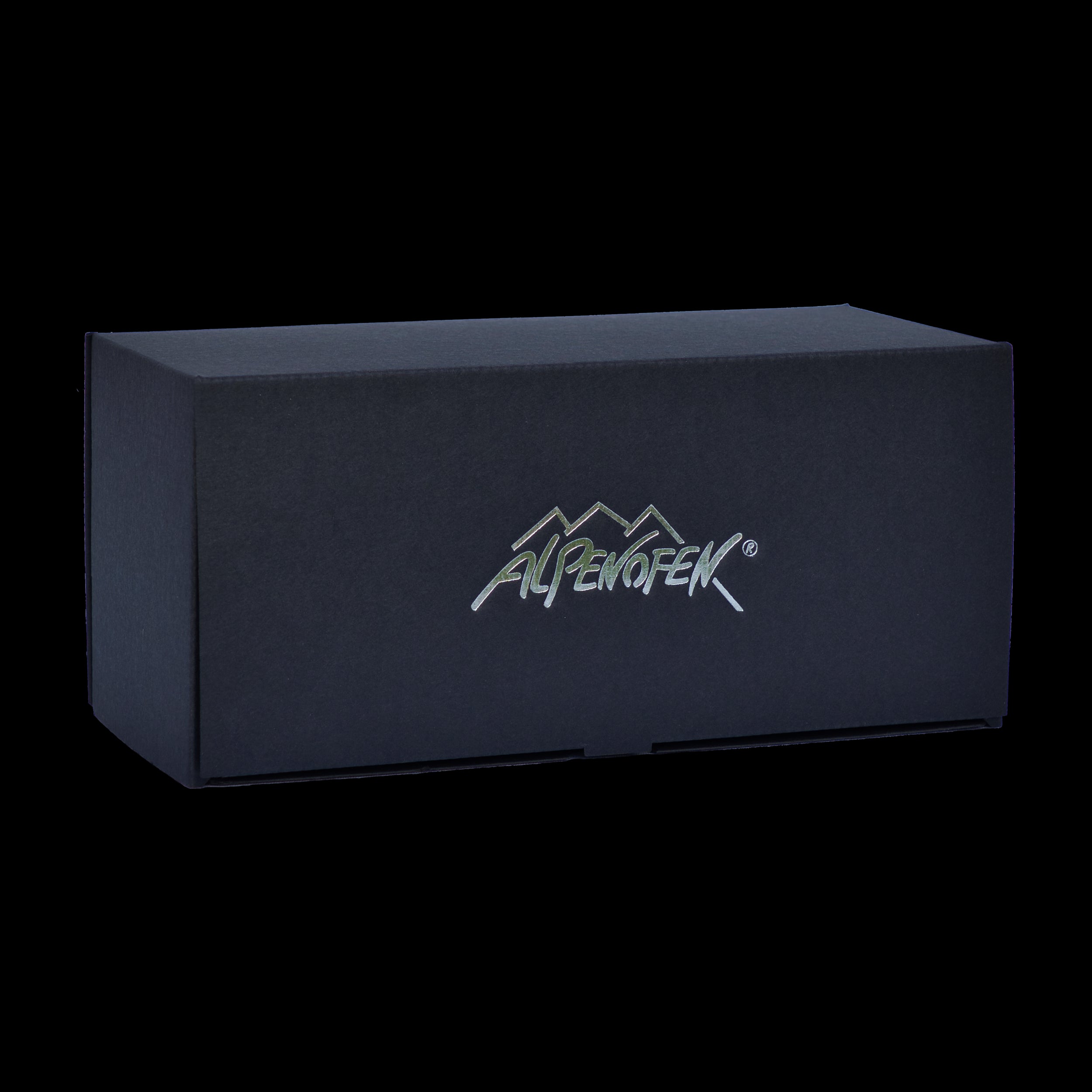 Eine schwarze rechteckige Schachtel mit einem Logo mit Berggipfeln und „Alpenofen“ in Silber, das die exquisite Handarbeitstradition aus dem Erzgebirge zur Schau stellt und die Qualität von „Alpenofen eckig“ widerspiegelt.