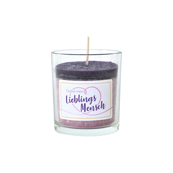 Das Partylicht Wildblumen von The Candle Factory besteht aus einem Glashalter mit einer violetten und rosa Kerze aus pflanzlichem Stearin. Sie trägt die Botschaft „Du bist mein Lieblingsmensch“ in dekorativer Schrift, umgeben von einem Herzen, mit einem Docht in der Mitte, alles in Deutschland hergestellt.