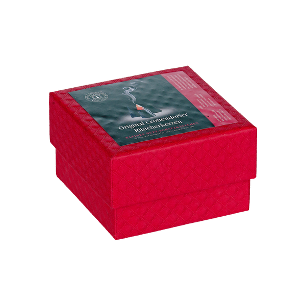 Die Geschenkbox „Riesen“ von Original Crottendorfer Räucherkerzen ist eine rote, quadratische Geschenkbox mit Deckel. Ein grünes Etikett mit Rauch und deutschem Text deutet darauf hin, dass sie Räucherkerzen enthält, die sich ideal für festliche Weihnachtsdüfte eignen.