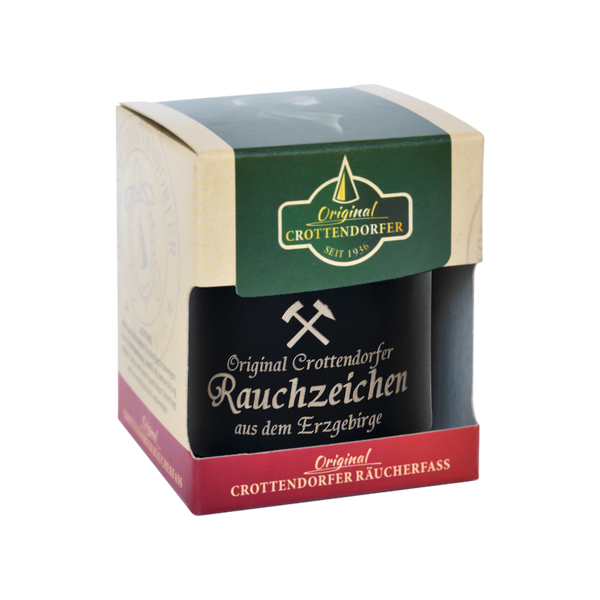 Das Räucherfass Erzgebirgische Sprüche von Original Crottendorfer Räucherkerzen ist eine kleine schwarze Schachtel mit grünen und roten Akzenten, auf der das ikonische Hammersymbol der Marke abgebildet ist. Es ist perfekt für echtes Räuchervergnügen mit Ihrem Lieblings-Räucherkerzenhalter.