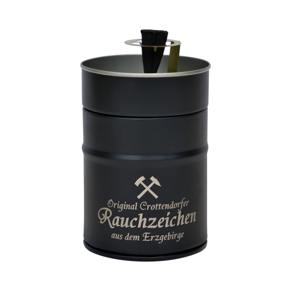 Das Räucherfass Erzgebirgische Sprüche von Original Crottendorfer Räucherkerzen ist ein schwarzer, zylindrischer Halter mit silbernen Akzenten und trägt den Text „Original Crottendorfer Rauchzeichen aus dem Erzgebirge“ sowie ein eingraviertes Symbol gekreuzter Hämmer und verspricht ein elegantes Räuchervergnügen.