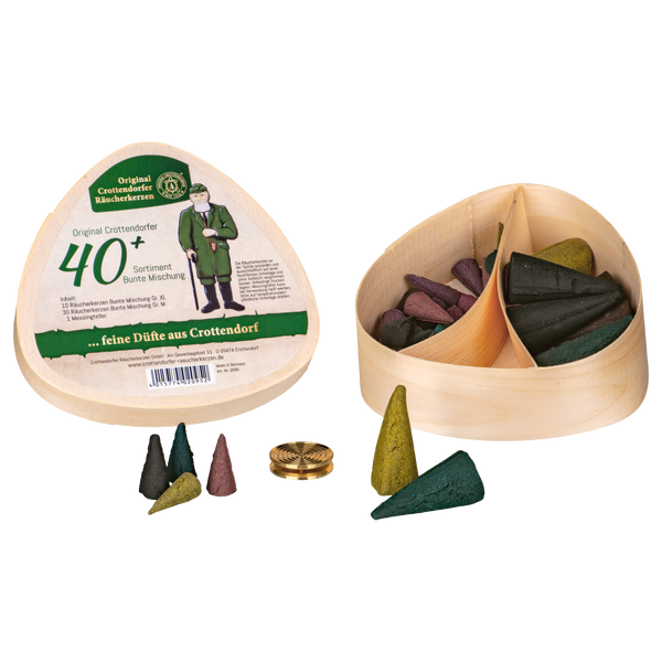 Das Geschenkset Spanschachtel 40+ von Original Crottendorfer Räucherkerzen ist ein dreieckiges Holzkästchen mit unterteilten Abschnitten, die bunte Räucherkegel enthalten. Der Deckel zeigt einen deutschen Text und das Bild eines Mannes, daneben Kegel und einen Messingteller.