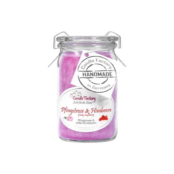 Eine rosa Duftkerze/ein Windlicht „Pfingstrose & Himbeere“ Baby-Jumbo von Candle Factory wird in einem Glasgefäß mit Deckel und Henkel geliefert, mit Pfingstrosen- und Himbeermotiven auf dem Etikett und einem daran befestigten „Handmade in Germany“-Anhänger.