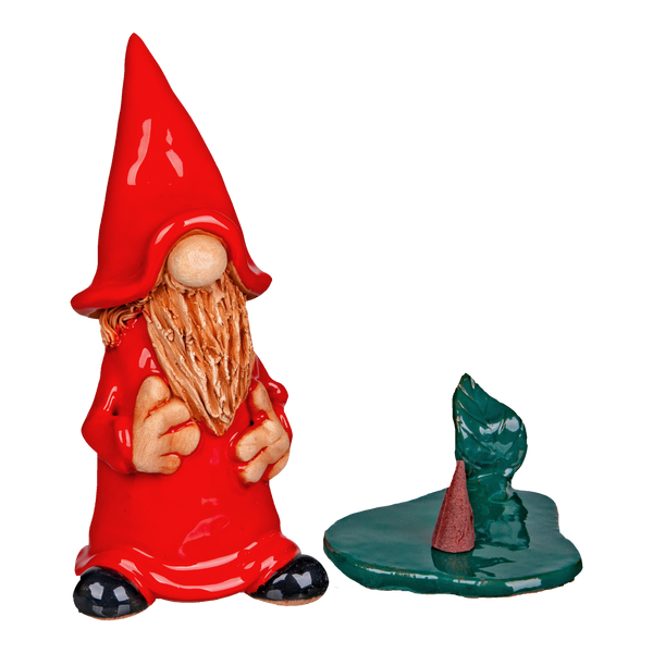 Die Keramik-Räucherfigur Wichtel – rot von Original Crottendorfer Räucherkerzen zeigt einen charmanten, langbärtigen Gnom mit rotem Hut und Umhang, begleitet von einer kleinen grünen Plattform mit einem schrägen roten Kegel vor einem tiefschwarzen Hintergrund.