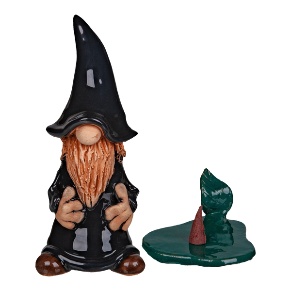 Die Keramik-Räucherfigur Wichtel - schwarz von Original Crottendorfer Räucherkerzen steht neben einem glänzend grünen, unregelmäßigen Podest mit subtilen Variationen in Form und Farbe. Der Hintergrund ist schwarz.