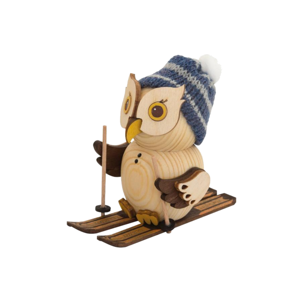 Die „Mini Eule mit Ski“ von Drechslerei Kuhnert zeigt eine skurrile Eulenfigur aus Holz aus der MINI Eulen Kollektion. Sie trägt eine blaue Strickmütze mit weißem Bommel, gleitet mit Stöcken auf Skiern dahin und verkörpert eine verspielte Wintersportstimmung, die den charmanten Holzfiguren ähnelt.
