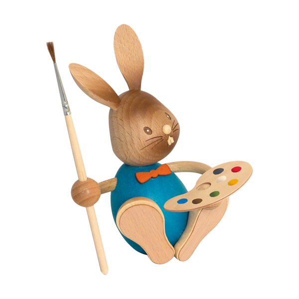Der Stupsi Hase Eiermaler von Drechslerei Kuhnert ist eine bezaubernde Hasenfigur aus Holz mit blauer Weste und orangefarbener Fliege, die einen Pinsel und eine bunte Palette hält und aus nachhaltigem Holz gefertigt ist.