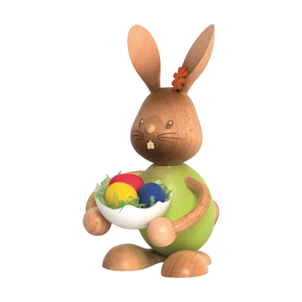 Der Stupsi Hase mit Eierschale von Drechslerei Kuhnert ist eine Holzfigur mit grünem Körper und einer Schale mit bunten Ostereiern. Er hat eine Blume am Ohr, einen fröhlichen Gesichtsausdruck und zeigt feine Handwerkskunst.