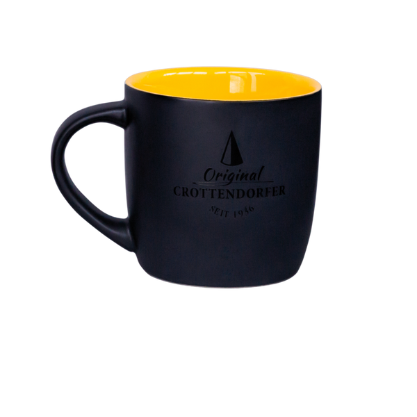 Die Keramiktasse matt gelb/schwarz von Original Crottendorfer Räucherkerzen zeigt vorn Logo und "Original Crottendorfer seit 1946", hat breite Henkel, ist spülmaschinengeeignet und auf schlichtem Hintergrund abgebildet.