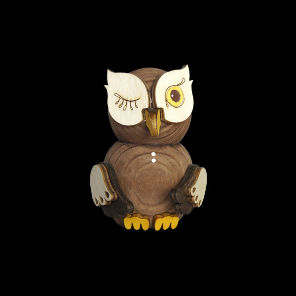 Die Mini Eule gebeizt von Drechslerei Kuhnert ist eine hölzerne Eulenfigur mit verspieltem Design, bei der ein Auge offen ist und das andere zwinkert. Sie ist aus nachhaltig gewonnenem Holz gefertigt und hat einen gelb bemalten Schnabel und Füße, einen glatten, runden Körper und aufwendige Schnitzereien, die den exquisiten Stil der Marke zur Schau stellen.