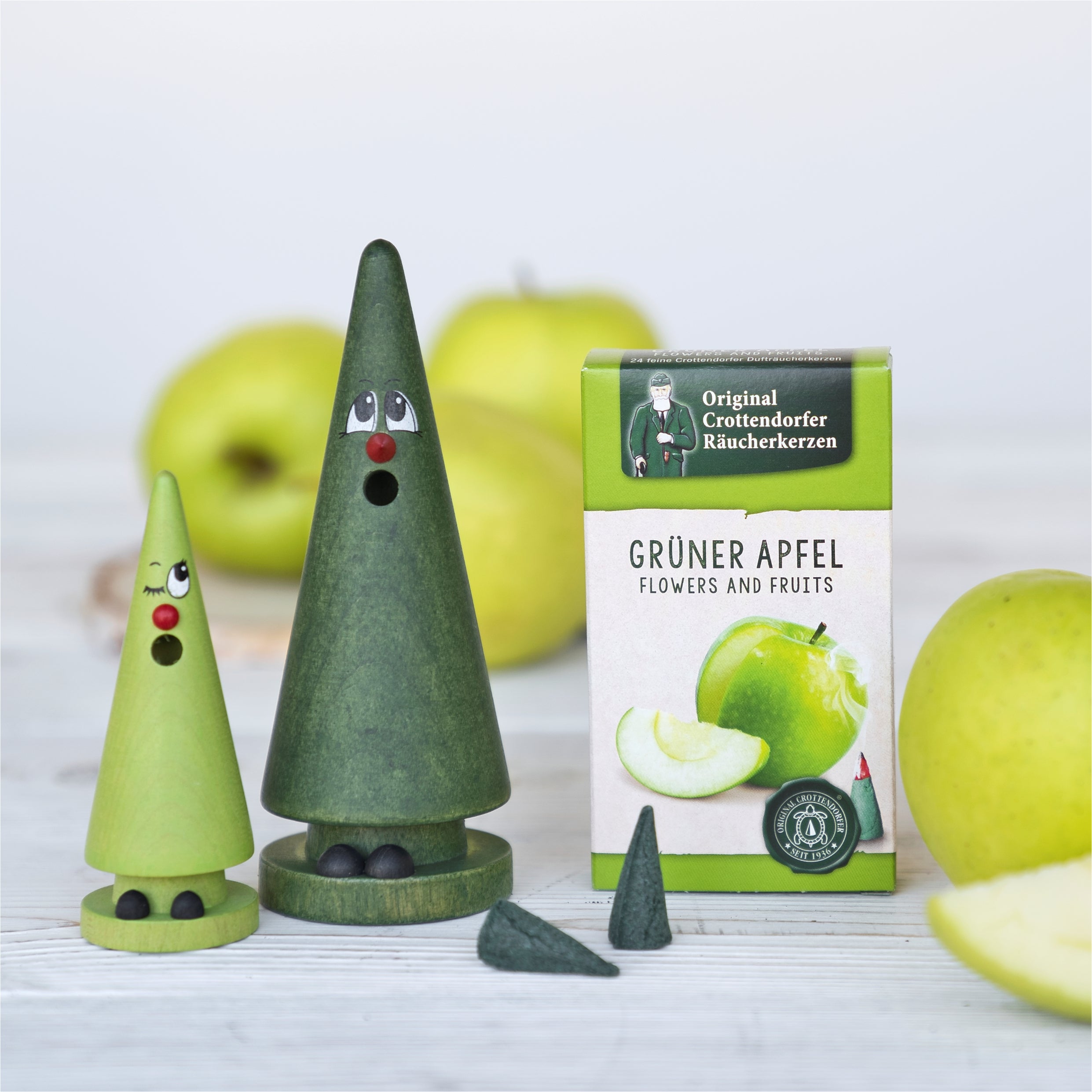 Räucherfigur Crottendorfer Mini-Ziegenbein Wilma Waldmoos (lindgrün) arrangiert mit Ziegenbein Tina Tanne, dunkelgrün und Räucherkerzen Grüner Apfel vor grünen Äpfeln