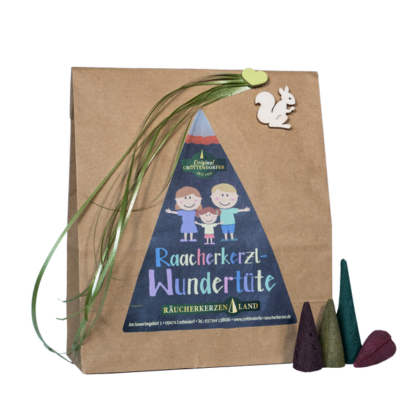Die Räucherkerzl-Wundertüte von Original Crottendorfer Räucherkerzen besteht aus einer braunen Tüte mit Comic-Kindern, grüner Schleife, Holz-Eichhörnchen und drei Duftkegeln (lila, grün, braun) – eine wunderbare Geschenkidee.