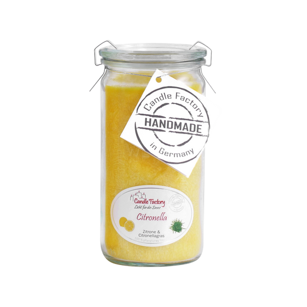 Die Duftkerze/Windlicht „Citronella“ Mini Jumbo von Candle Factory ist eine große Kerze im Glas mit gelbem Wachs und einem Metallverschluss. Sie ist mit Zitronen- und Zitronengrasmotiven versehen und trägt ein Etikett mit der Aufschrift „Candle Factory, Handmade in Germany“, was darauf hinweist, dass sie aus Kerze aus reinem pflanzlichem Stearin hergestellt ist.