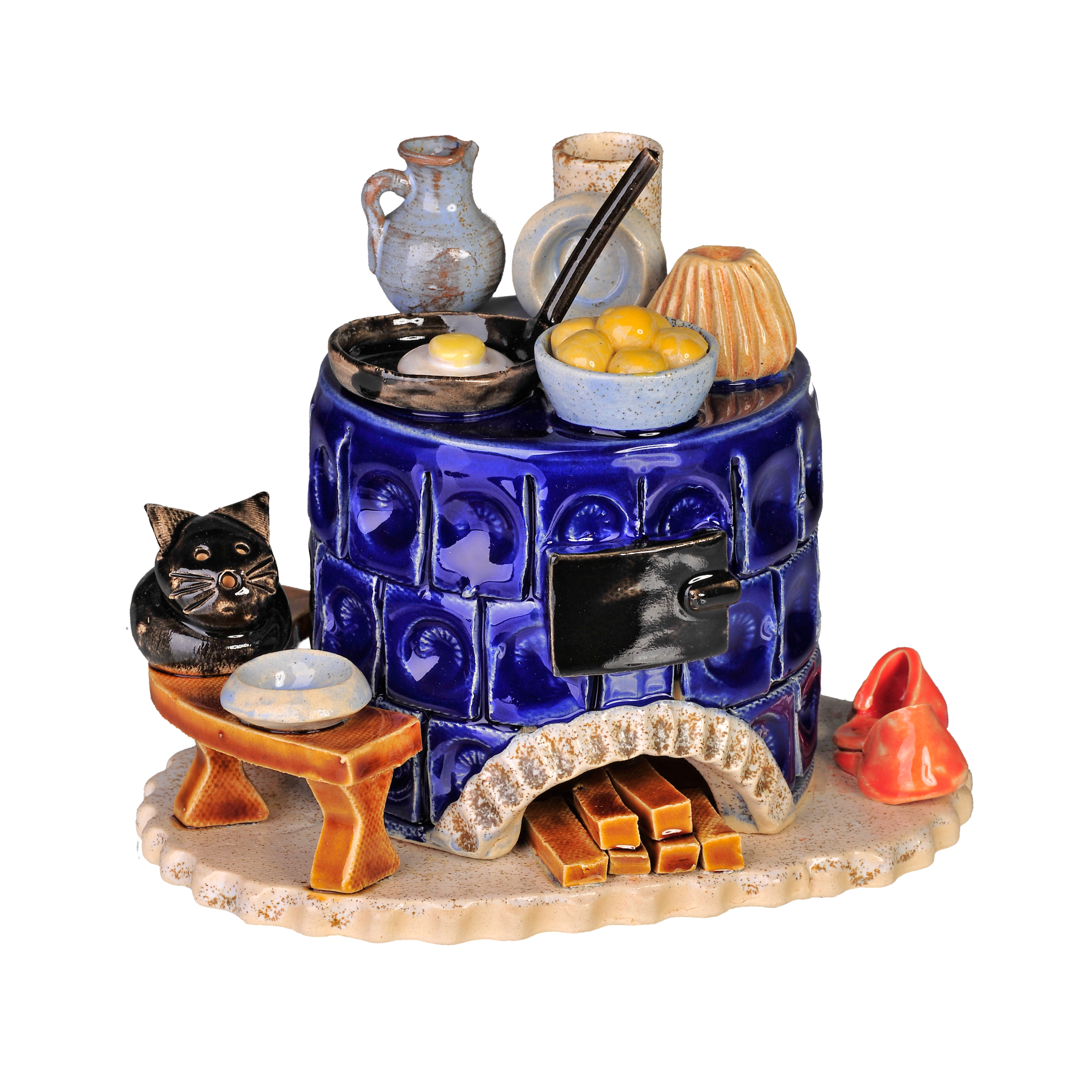 Der Keramik-Räucherofen, Mini rund, blau der Keramikwerkstatt Carola Busch zeigt einen blauen Kachelofen mit Töpfen und Geschirr darauf, eine schwarze Katzenfigur daneben, Holzscheite darunter und ein kleines geschwungenes rotes Dekor, das an die Handwerkskunst des Erzgebirges erinnert.