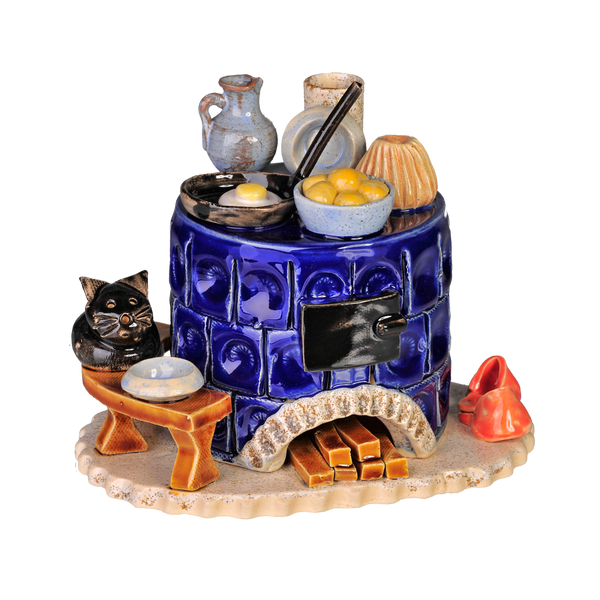 Der Keramik-Räucherofen, Mini rund, blau der Keramikwerkstatt Carola Busch zeigt einen blauen Kachelofen mit Töpfen und Geschirr darauf, eine schwarze Katzenfigur daneben, Holzscheite darunter und ein kleines geschwungenes rotes Dekor, das an die Handwerkskunst des Erzgebirges erinnert.