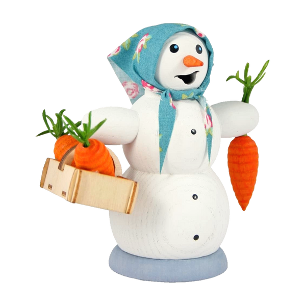 Die Räucherfigur Schneefrau mit Möhrenkorb von Drechslerei Kuhnert ist eine bezaubernde Schneemannfigur aus Holz im Stil der erzgebirgischen Volkskunst, geschmückt mit einem blauen Blumenschal. Dieses Rauchfiguren-Stück hält eine Holzkiste mit drei Karotten und eine Karotte in der Hand und lächelt vor einem schlichten Hintergrund.