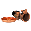 Eine zerbrochene „Räucherhexe mit Keramikteller - Hut schwarz“ von Original Crottendorfer, die einer Hexenfigur mit schwarzem Hut ähnelt, liegt neben einer orangefarbenen Schale mit Mini-Kürbissen. Dieses Unikat ist Teil unserer Limited Edition-Kollektion und in begrenzten Stückzahlen erhältlich.