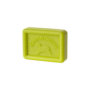 Eine grüne rechteckige Tafel Ovis Schafmilchseife Gurke-Limette mit „SCHAFMILCHSEIFE“ und einem geprägten Schaf auf der Vorderseite, bekannt für seine hautpflegenden Eigenschaften, isoliert auf weißem Hintergrund.