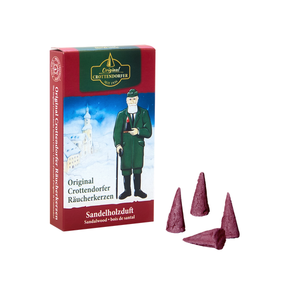Auf einer rot-grünen Schachtel ist ein Mann in Mantel und Hut mit einer Pfeife vor einem verschneiten Dorf abgebildet. Die Räucherkerzen mit der Aufschrift „Räucherkerzen Sandelholz“ von Original Crottendorfer Räucherkerzen bieten einen beruhigenden Sandelholzduft und vier kegelförmige Räucherstäbchen für eine beruhigende Atmosphäre.