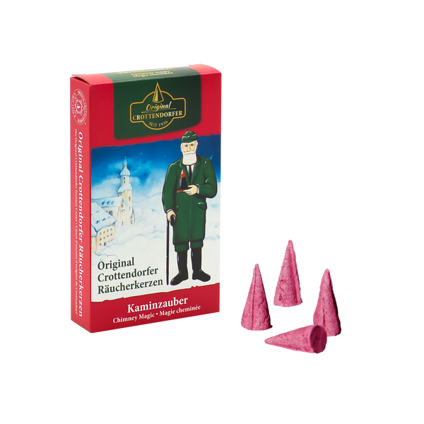 Die Räucherkerzen Kaminzauber von Original Crottendorfer Räucherkerzen im Vintage-Design mit Männchen und verschneitem Dorf lassen an Zimt-Ferien denken. Fünf rosa Zapfen neben der Box erinnern an gemütliche Glühweinabende am Kaminfeuer.