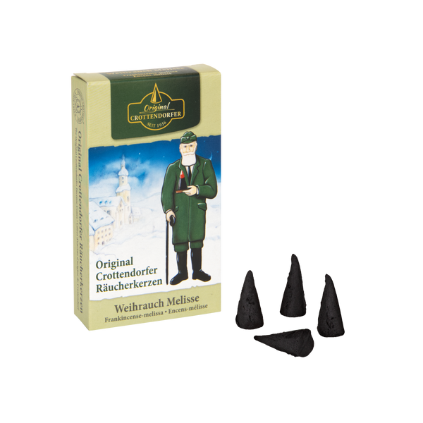 Eine Schachtel mit den Räucherkerzen Weihrauch Melisse von Original Crottendorfer Räucherkerzen verströmt einen wohltuenden Weihrauchduft und zeigt eine traditionelle Figur und eine verschneite Kirchenszene mit drei schwarzen Kegeln davor.