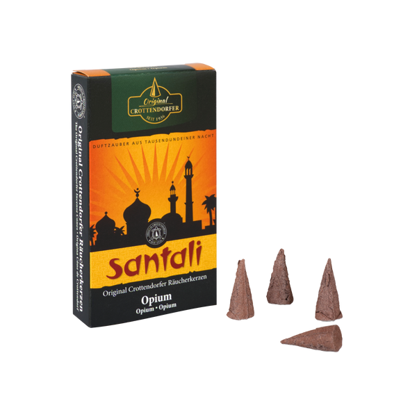 Schachtel mit Original Crottendorfer Räucherkerzen mit der Aufschrift „Räucherkerzen Opium“. Die Verpackung zeigt die Silhouette einer Moschee vor einem Sonnenuntergang und erinnert so an einen orientalischen Duft. Neben der Schachtel liegen drei braune Räucherkegel.