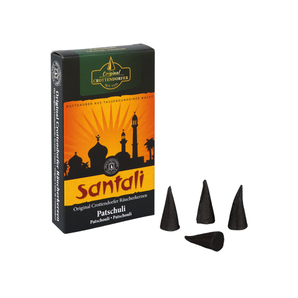 Eine Schachtel Original Crottendorfer Räucherkerzen Patschuli, mit einem orange-schwarzen Design, das orientalische Architektursilhouetten zeigt. Vier schwarze Räucherkegel für aphrodisierende Wirkung sind neben der Packung platziert.
