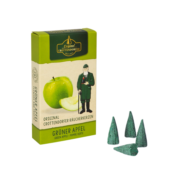 Eine grüne Schachtel Original Crottendorfer Räucherkerzen Grüner Apfel, auf der grüne Äpfel und ein Mann in Grün abgebildet sind, steht neben vier grünen kegelförmigen Räucherstäbchen auf weißem Grund, die einen frischen Apfelduft suggerieren.