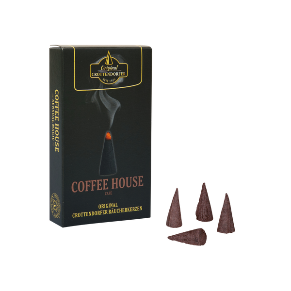 Neben vier braunen, kegelförmigen Räucherstäbchen steht eine schwarze Schachtel mit der Aufschrift „Räucherkerzen Coffee House“ von Original Crottendorfer Räucherkerzen. Die Schachtel ist mit goldfarbener Schrift und der Abbildung eines brennenden Räucherkegels verziert, aus dem Rauch aufsteigt, was den warmen und einladenden Kaffeehaus-Duft heraufbeschwört.