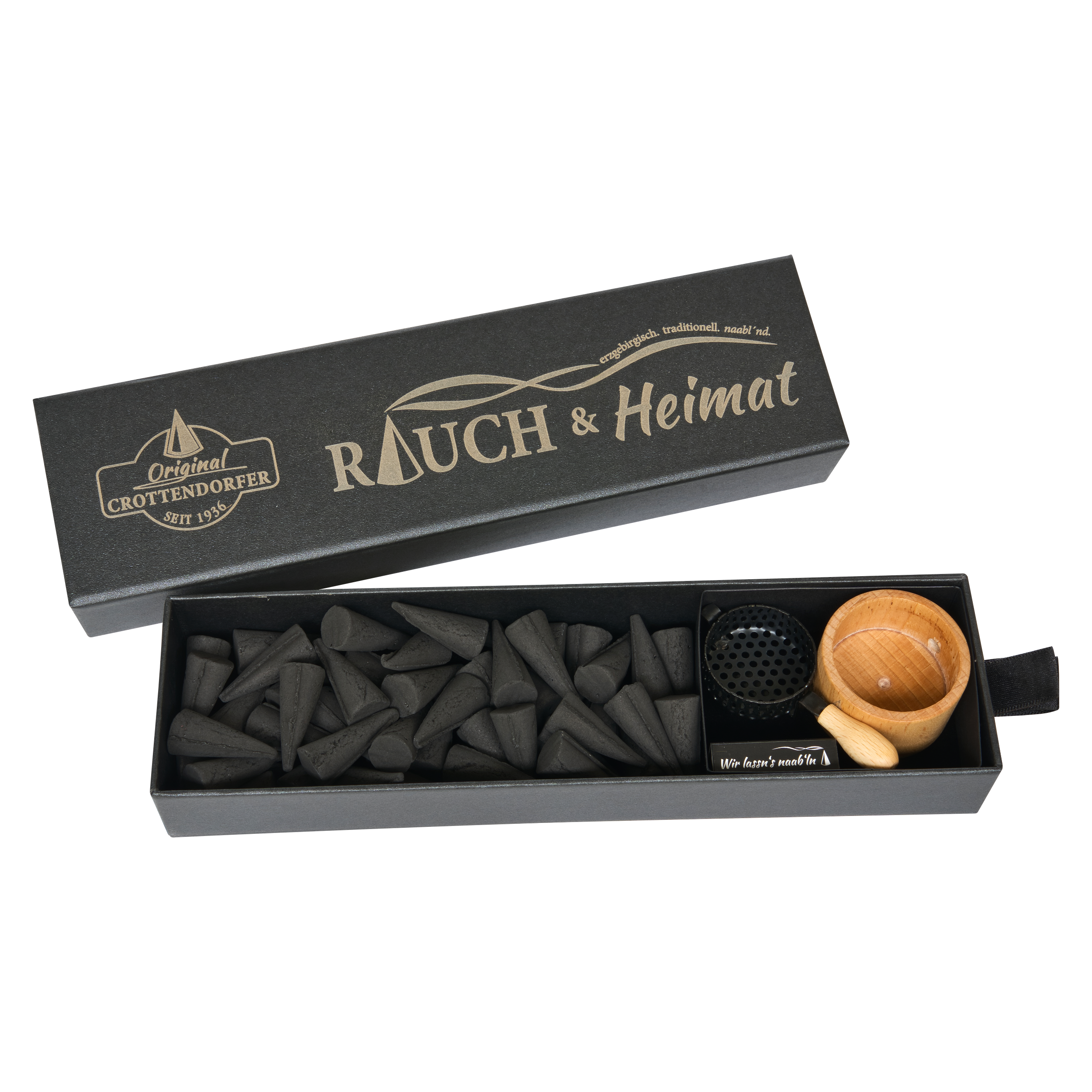 Die Schubbox „RAUCH & Heimat“ von Original Crottendorfer Räucherkerzen ist eine rechteckige schwarze Schachtel mit dem „Rauch & Heimat“-Logo. Im Inneren finden Sie schwarze Räucherkegel, eine kleine Holzschale, einen eleganten schwarzen Metallhalter und einen zierlichen Holzlöffel – unverzichtbare Räucheraccessoires, die sorgfältig zu einem eleganten Geschenk zusammengestellt wurden. Jeder Artikel ist ordentlich in der Schachtel angeordnet und sorgt so für ein raffiniertes Geschenk-Erlebnis.