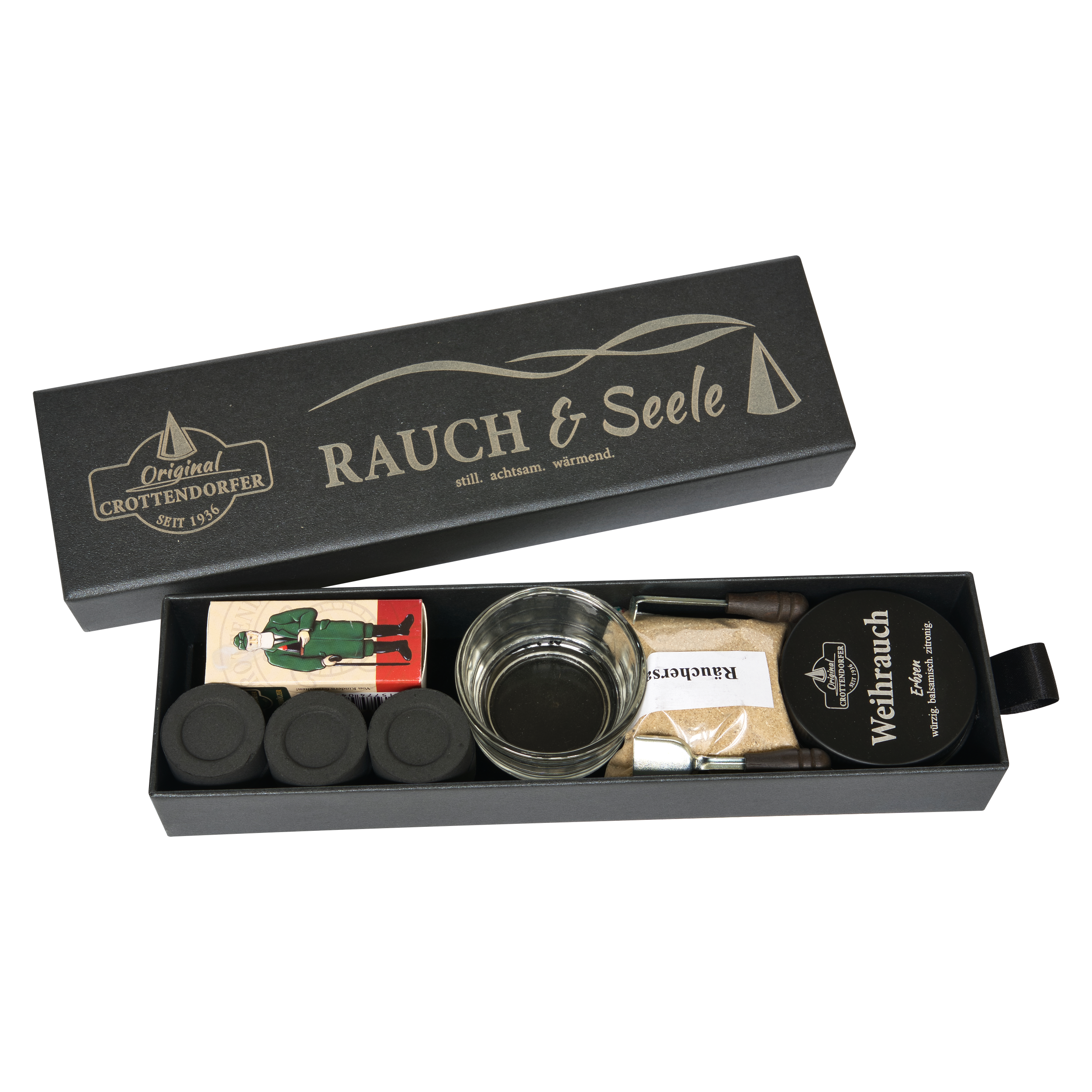 Eine rechteckige schwarze Schubbox „RAUCH & Seele“ von Original Crottendorfer Räucherkerzen enthält ein Geschenkset mit Räucherutensilien, bestehend aus Räucherkegeln, einem Metallhalter, einer Holzpinzette, Streichhölzern und einer runden Dose mit der Aufschrift „Weihrauch Extra“. Die Artikel sind ordentlich in der offenen Schachtel angeordnet.