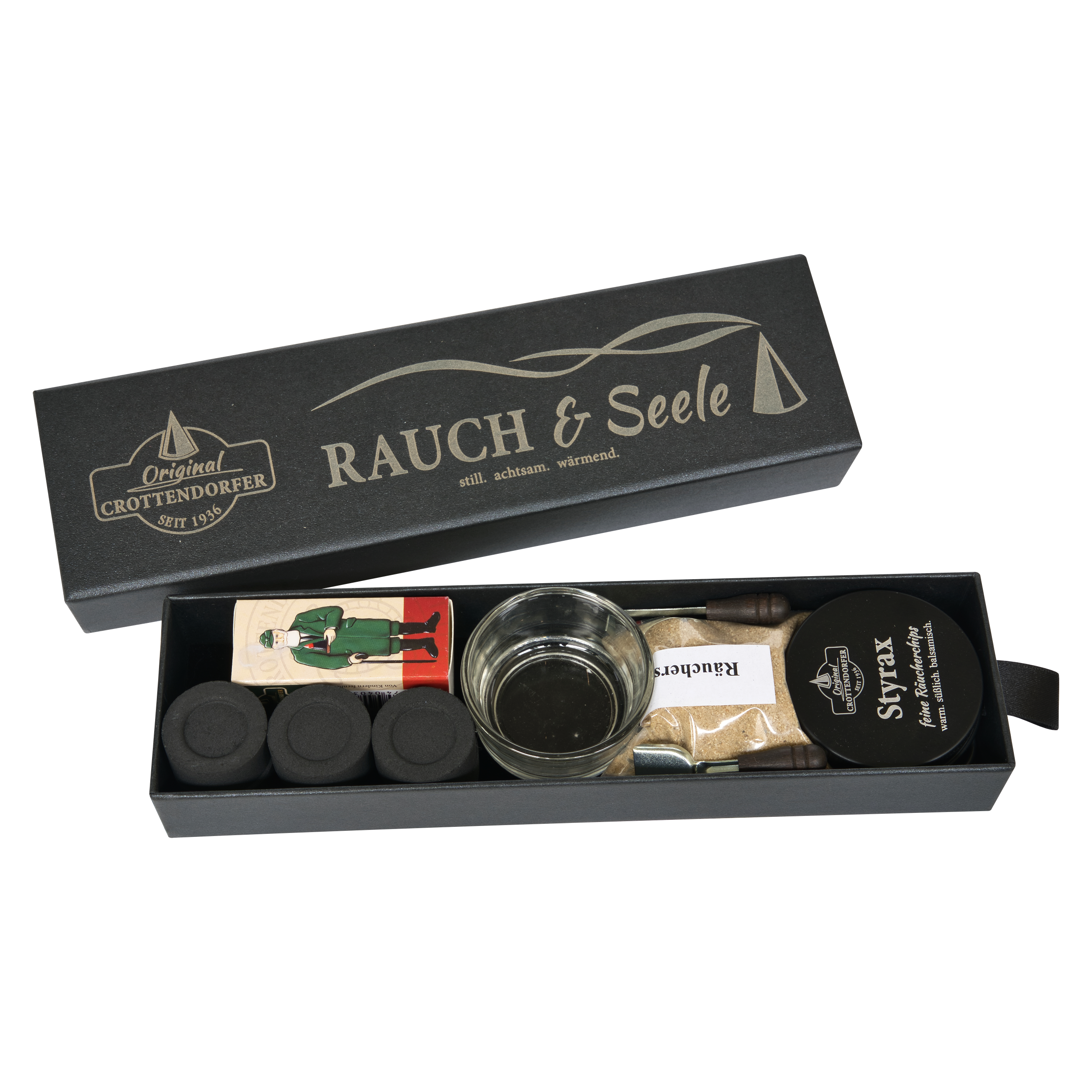 Eine schicke schwarze „Schubbox RAUCH & Seele“ von Original Crottendorfer Räucherkerzen enthält eine sorgfältig zusammengestellte Auswahl an Räucherzubehör, darunter Räucherkegel, einen Glashalter, eine Holzfigur, Streichhölzer, einen Metallhalter und eine Packung mit der Aufschrift „St. Felix“ – alles wunderschön arrangiert in einer eleganten Geschenkbox vor weißem Hintergrund.