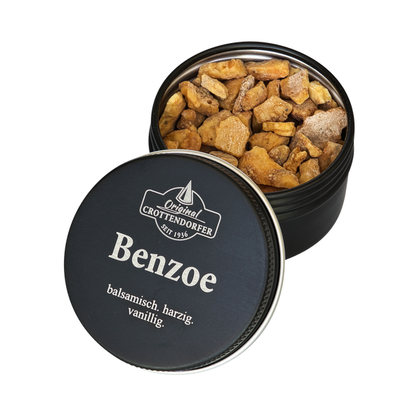 Eine runde schwarze Dose mit der Aufschrift „Benzoe in der Schraubdeckeldose“ von Original Crottendorfer Räucherkerzen, teilweise geöffnet, sodass hellbraune Harzstücke mit einem balsamischen, harzigen Duft und einem Hauch von Vanille zum Vorschein kommen – perfekt zum Räuchern.