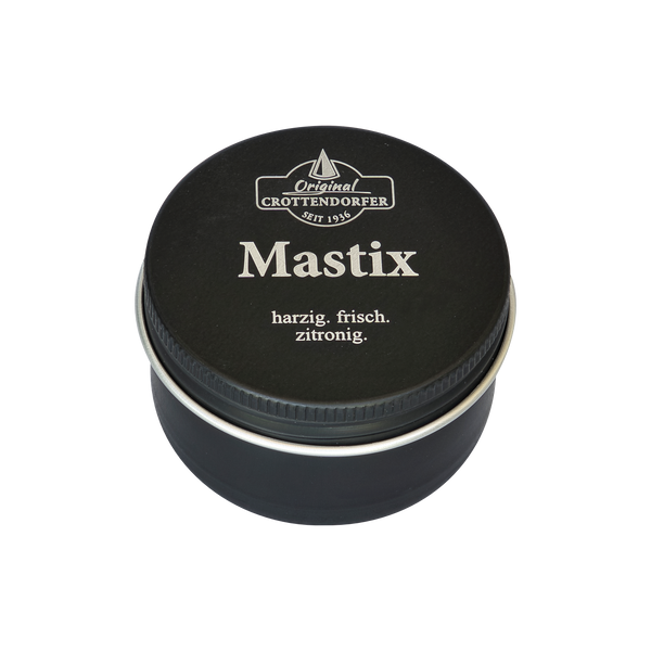 Eine runde schwarze Blechdose mit silbernem Rand und der Aufschrift „Mastix in der Schraubdeckeldose“ von Original Crottendorfer Räucherkerzen besticht durch ihr minimalistisches Design. Diese griechische Räuchermischung ist harzig, frisch und zitronig.